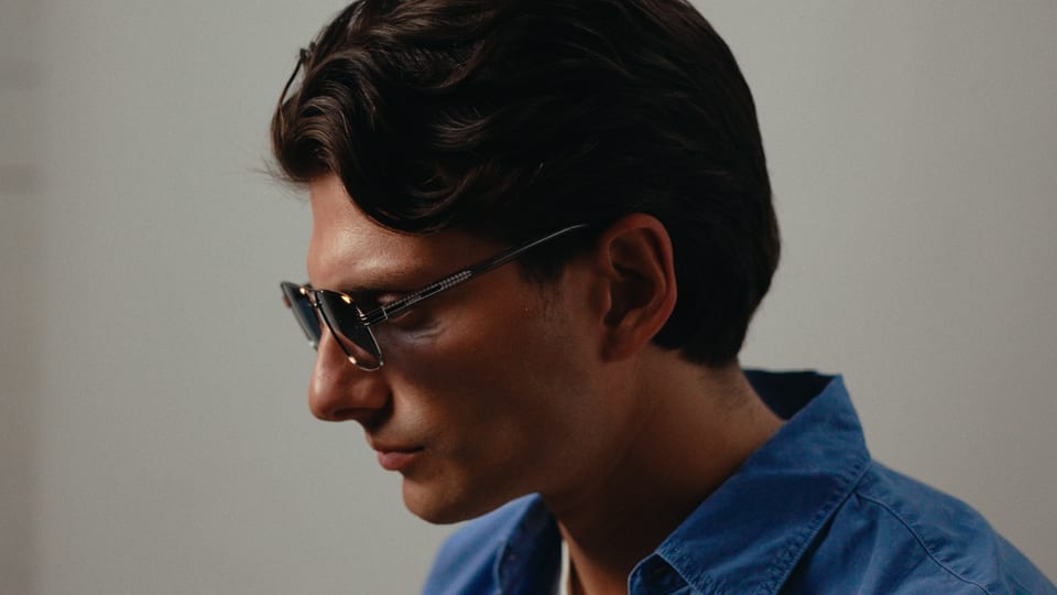 Model in sunglasses and a blue shirt, studio portrait